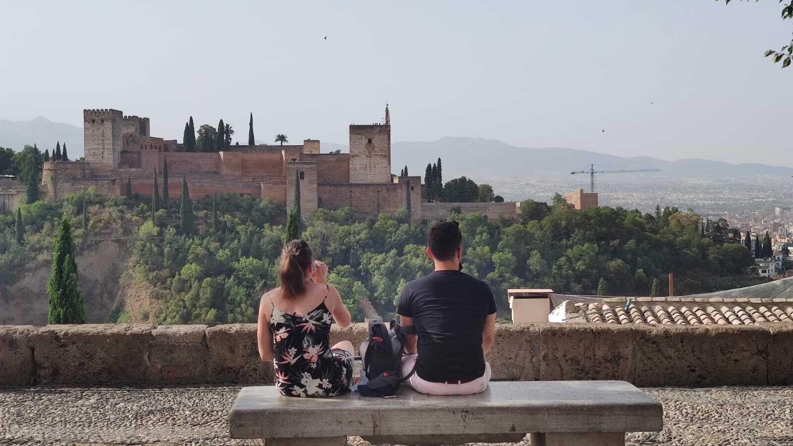 Dos jóvenes observan la Alhambra desde el mejor banco del mundo.