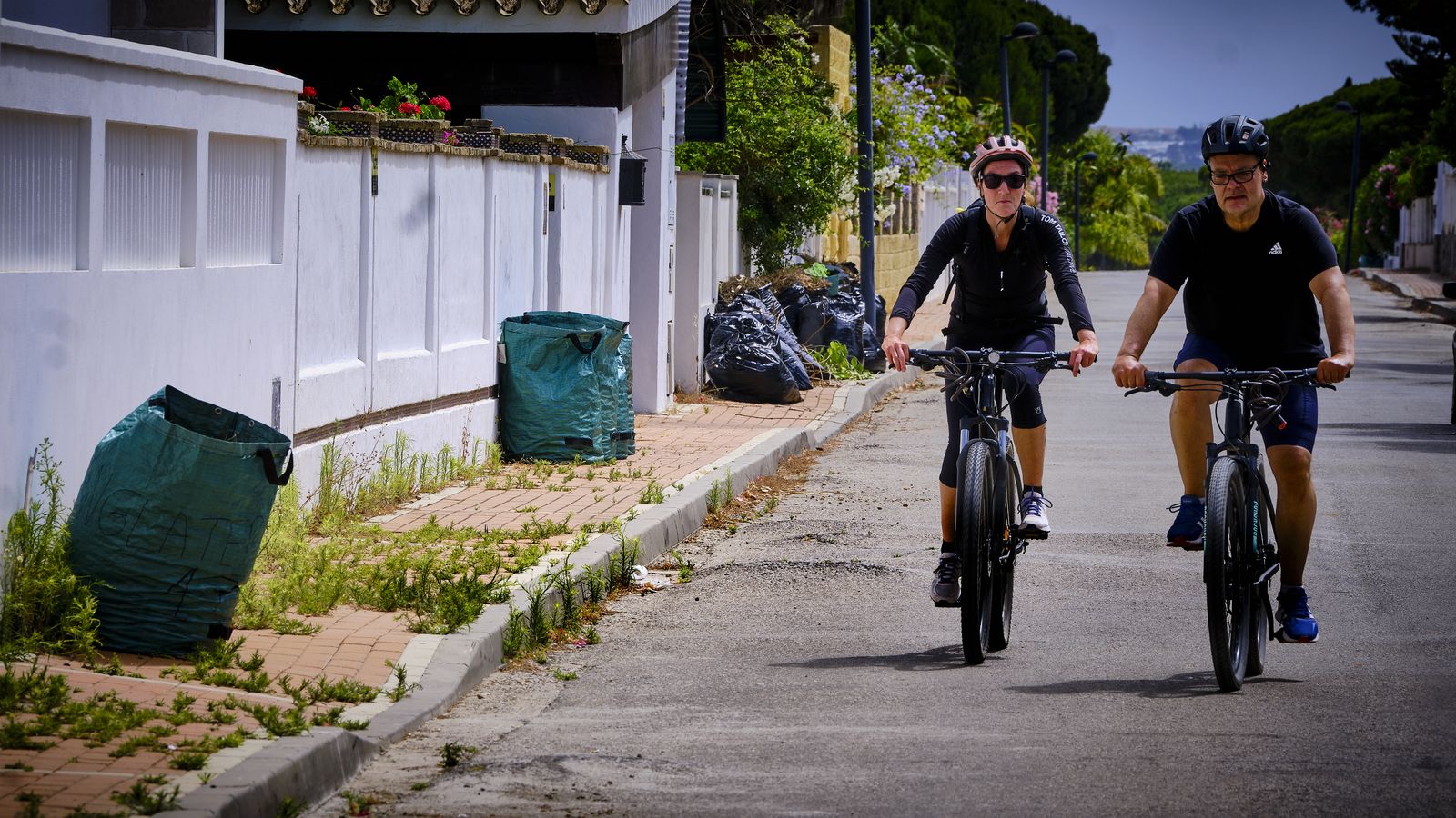 Bolsas de basura y restos de poda, acumuladas en una de las calles de la urbanización.