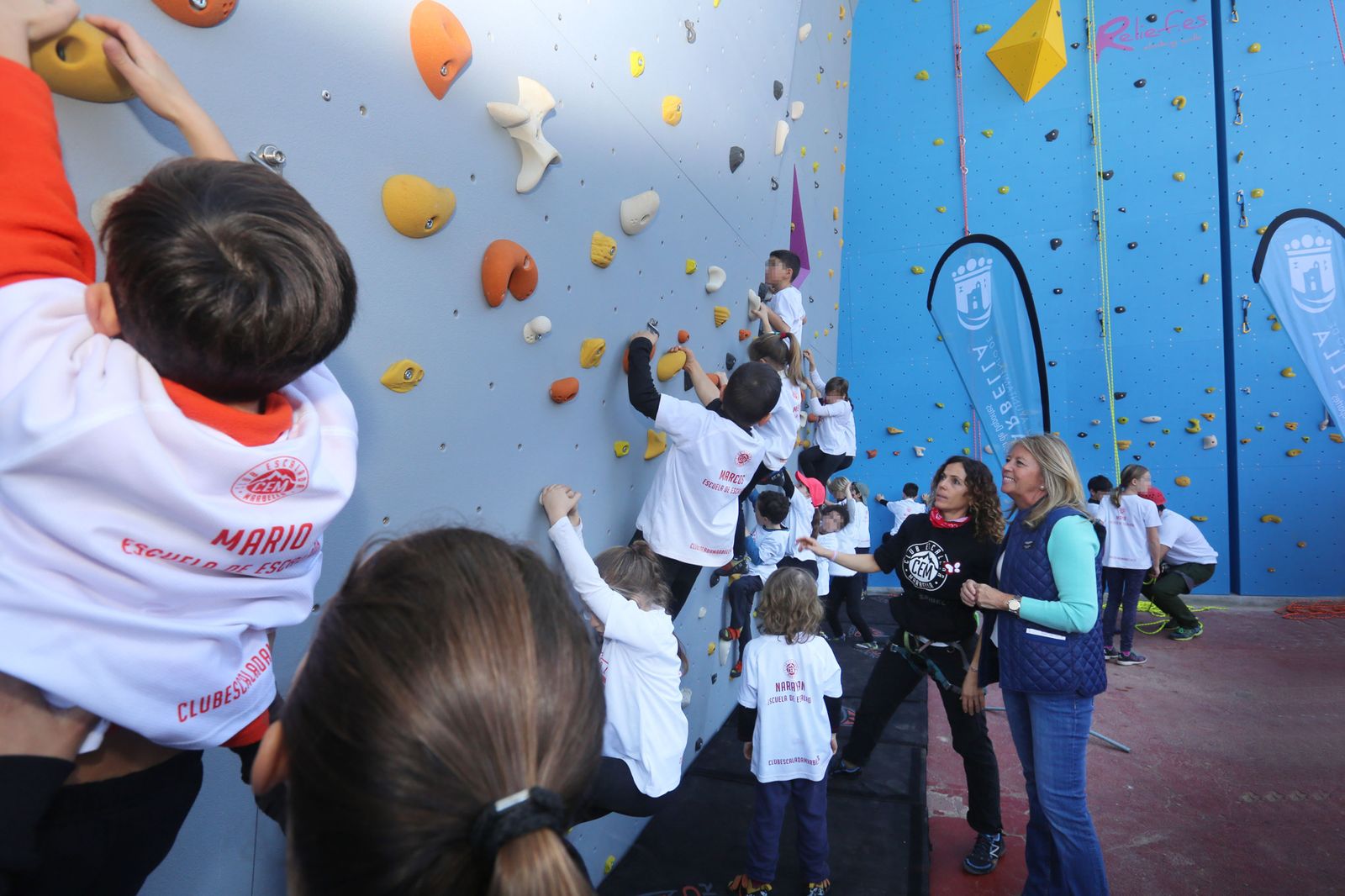 Varios niños suben por el rocódromo.
