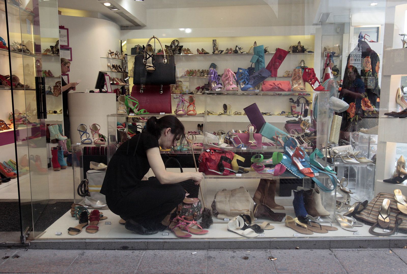 Una trabajadora coloca los productos en un escaparate de un comercio.