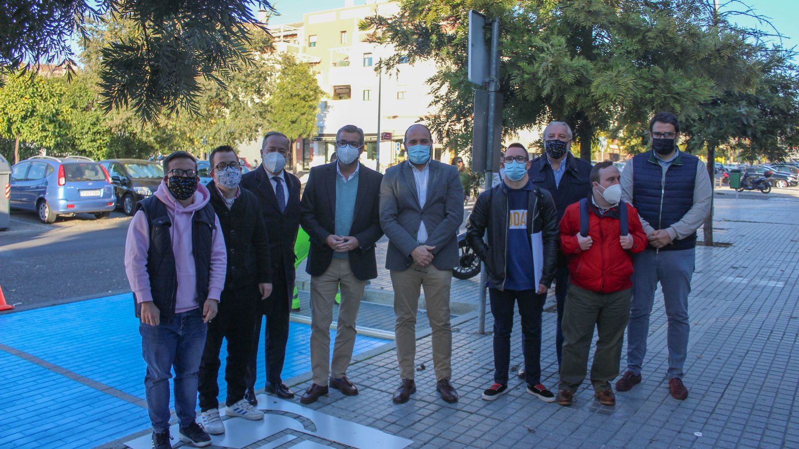 Jordano, Torrico y miembros de Down Córdoba, junto a un parking pintado de azul.