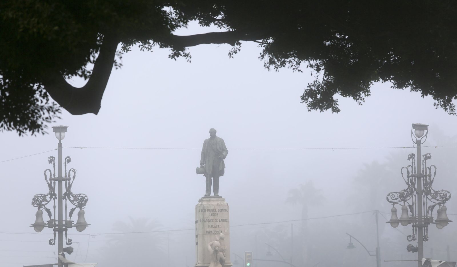 He aquí al Marqués de Larios erigido en faro entre la niebla: a uno y otro lado, cualquier ciudad posible parece dispuesta a tomar sitio.