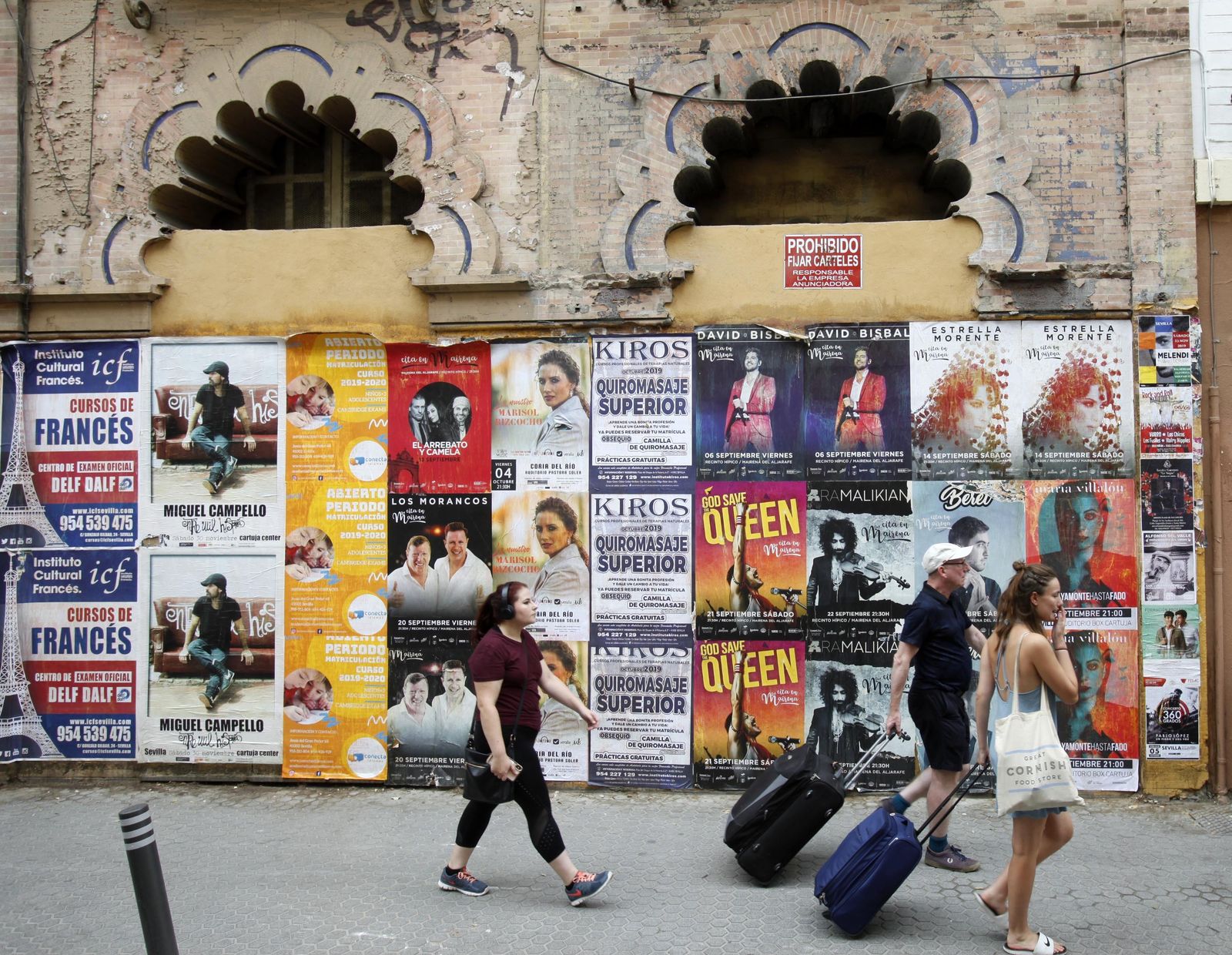 Turistas por Amor de Dios junto a los carteles musicales del edificio de Aníbal González.
