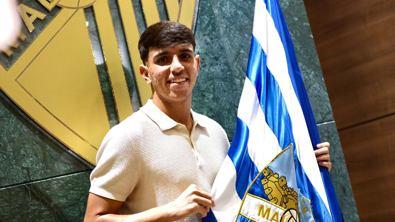 Izan Merino posa con la bandera del Málaga CF.