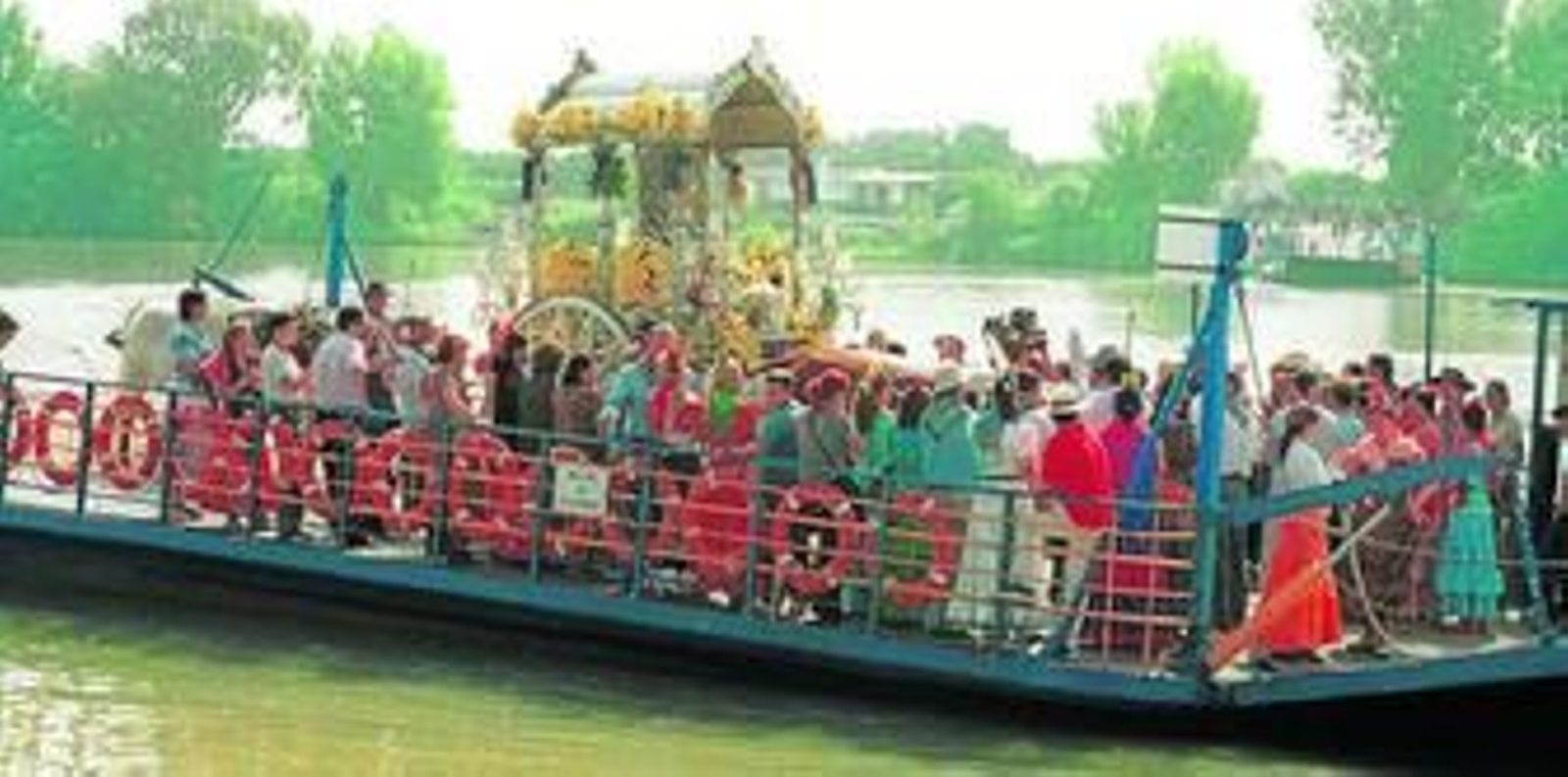 La Hermandad de Utrera atraviesa el Guadalquivir en una barcaza, a la altura de Coria del Río.