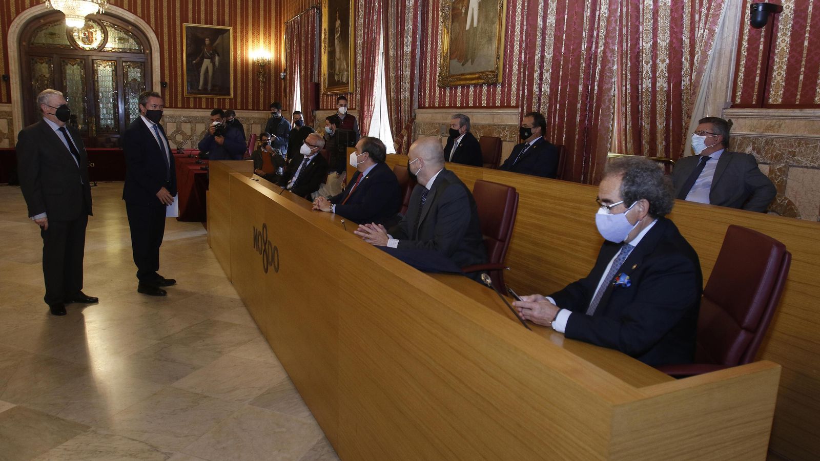 El alcalde, Juan Espadas; y el presidente del Consejo, Francisco Vélez, saludan a los hermanos mayores presentes en el acto celebrado en el Ayuntamiento.