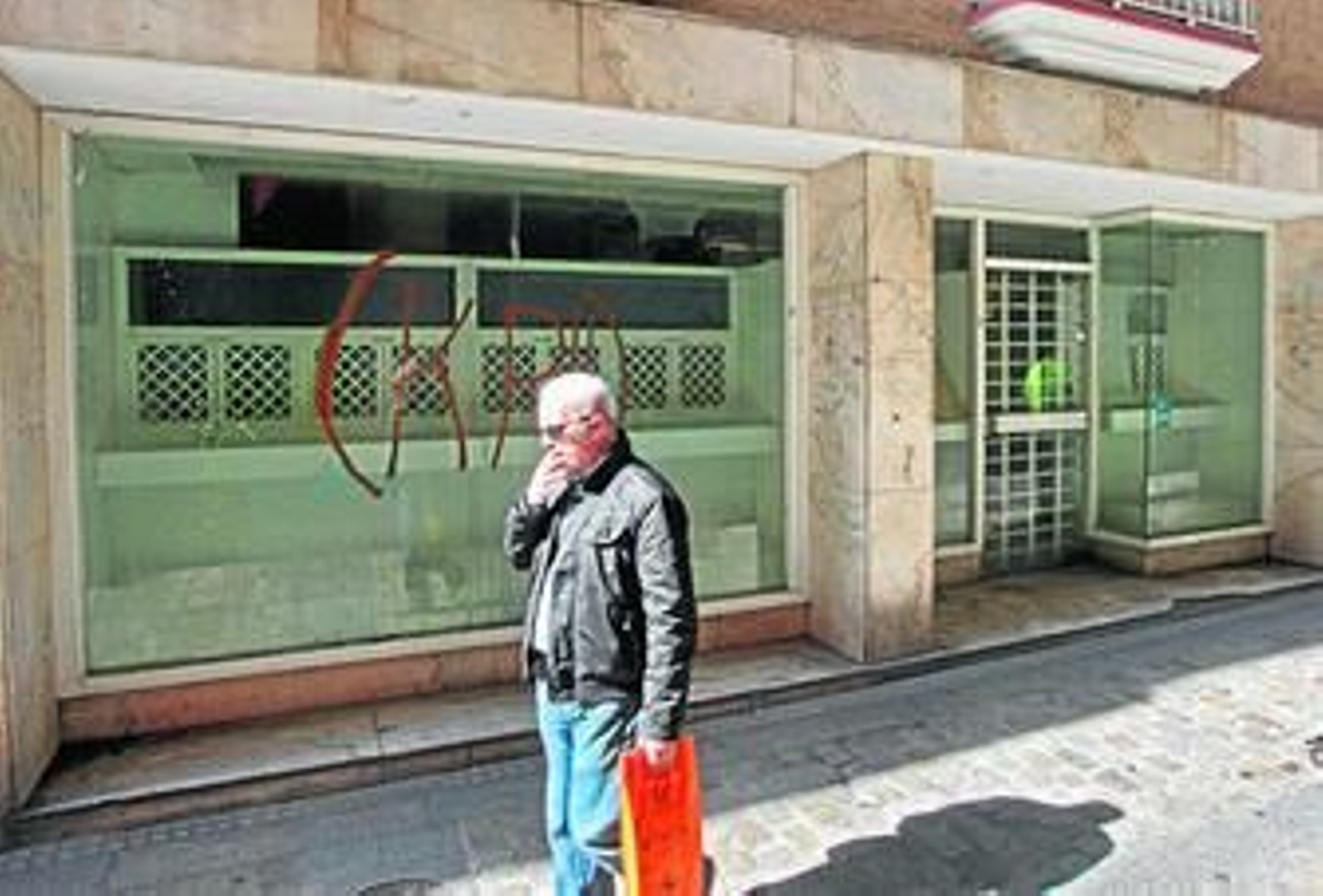 Uno de los comercios vacíos de la calle Sacramento, con pintadas en el escaparate.