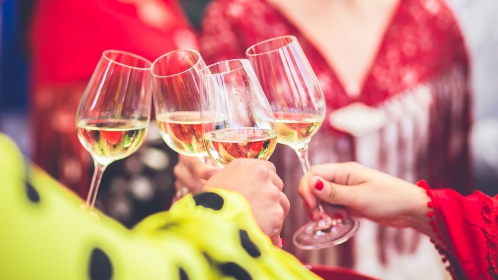 Mujeres vestidas de gitana brindan con unas copas de vino de Jerez.