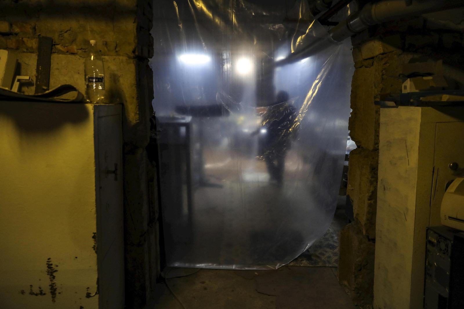 Una enfermera sentada detrás de una puerta de plástico improvisada en un hospital en Ucrania.