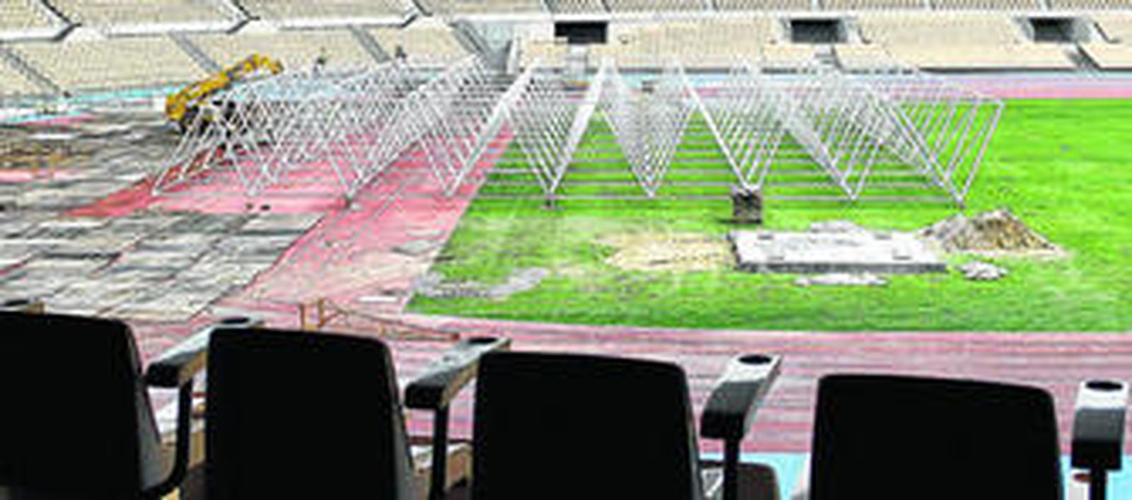 Una grúa coloca parte de la estructura que forma parte de la cubierta adquirida por el Ayuntamiento de Sevilla para la final de la Copa Davis.