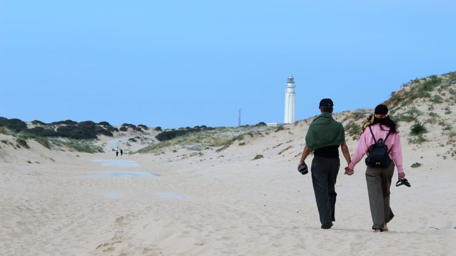 Un par de paseantes en el entorno dunar que rodea al faro. Un par de paseantes en el entorno dunar que rodea al faro.