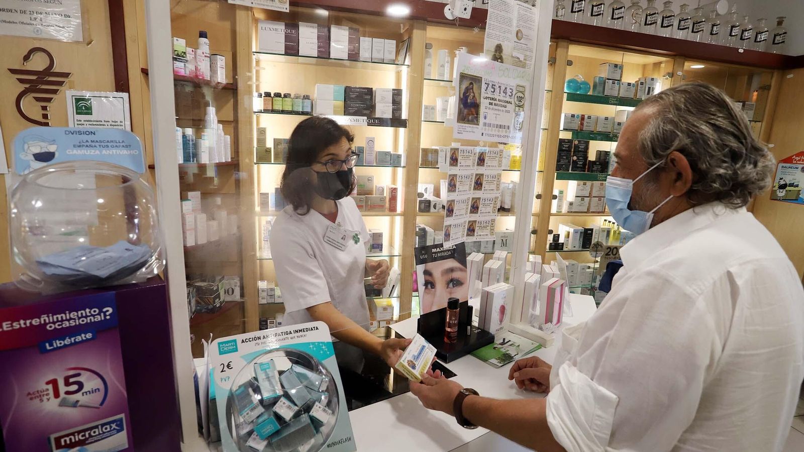 Un usuario adquiere uno de los test de Covid y gripe en una farmacia onubense.