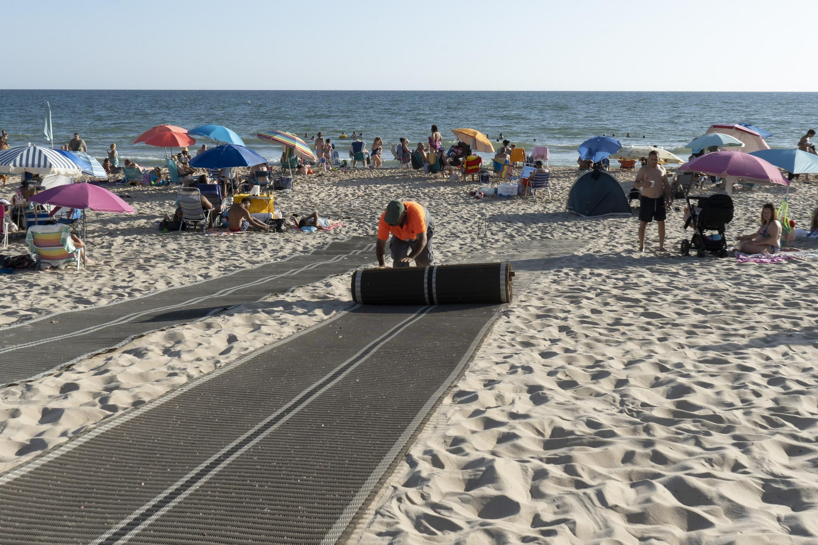 Una persona coloca las pasarelas accesibles en la playa de Matalascañas Una persona coloca las pasarelas accesibles en la playa de Matalascañas