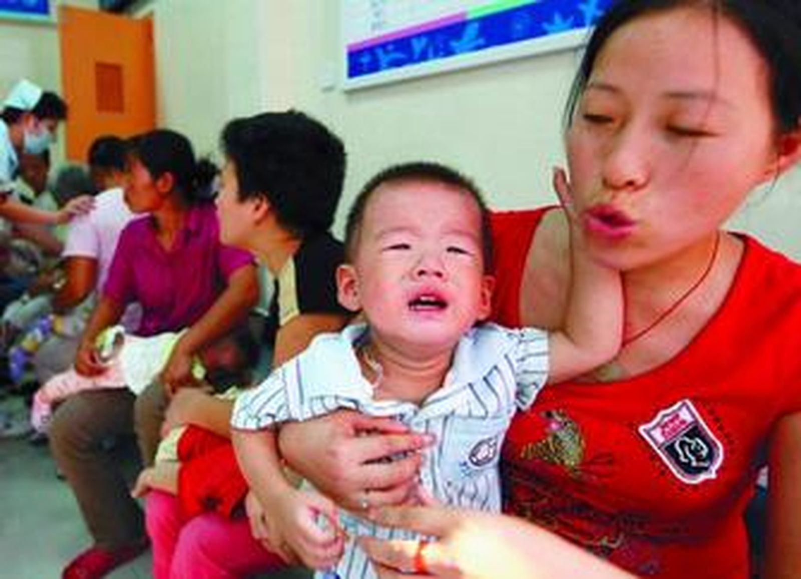 Esta madre china calma a su bebé, mientras espera que éste reciba tratamiento médico.