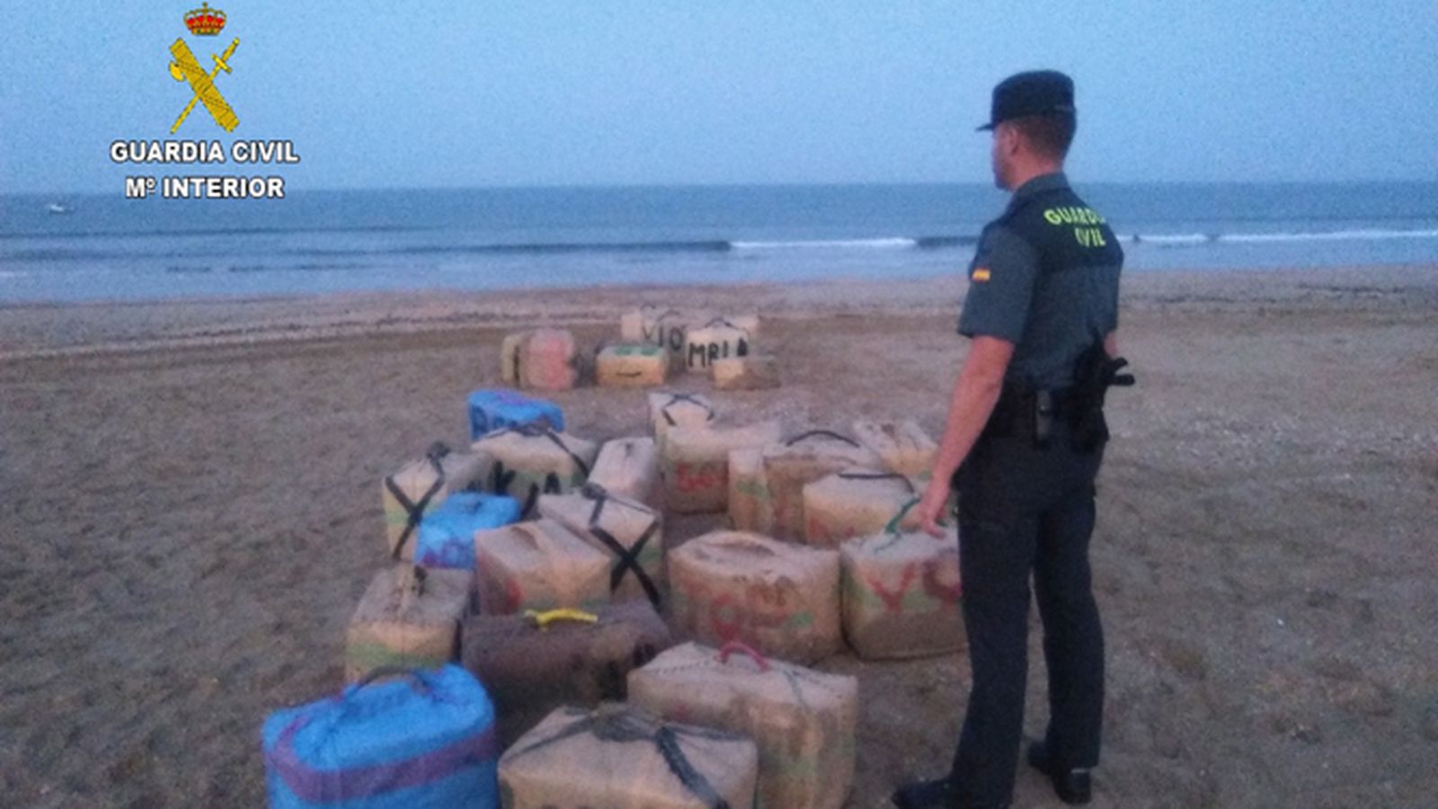 Un agente vigila los fardos de otro alijo hallado en Punta Umbría hace unos meses.