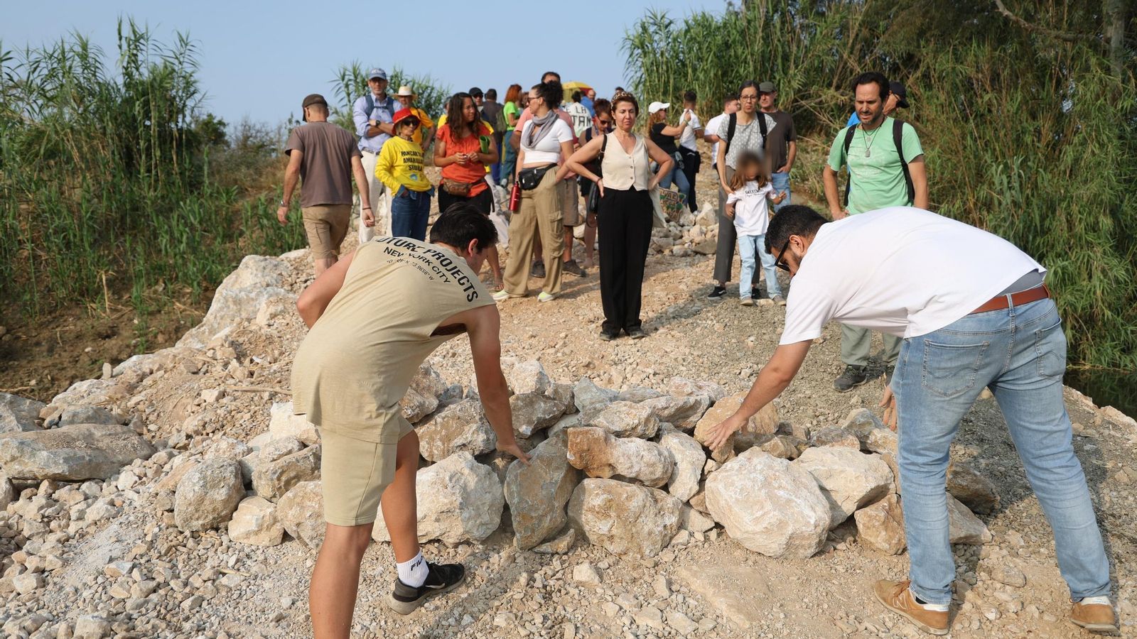 Manifestantes colocan piedras en una rampa junto al río.