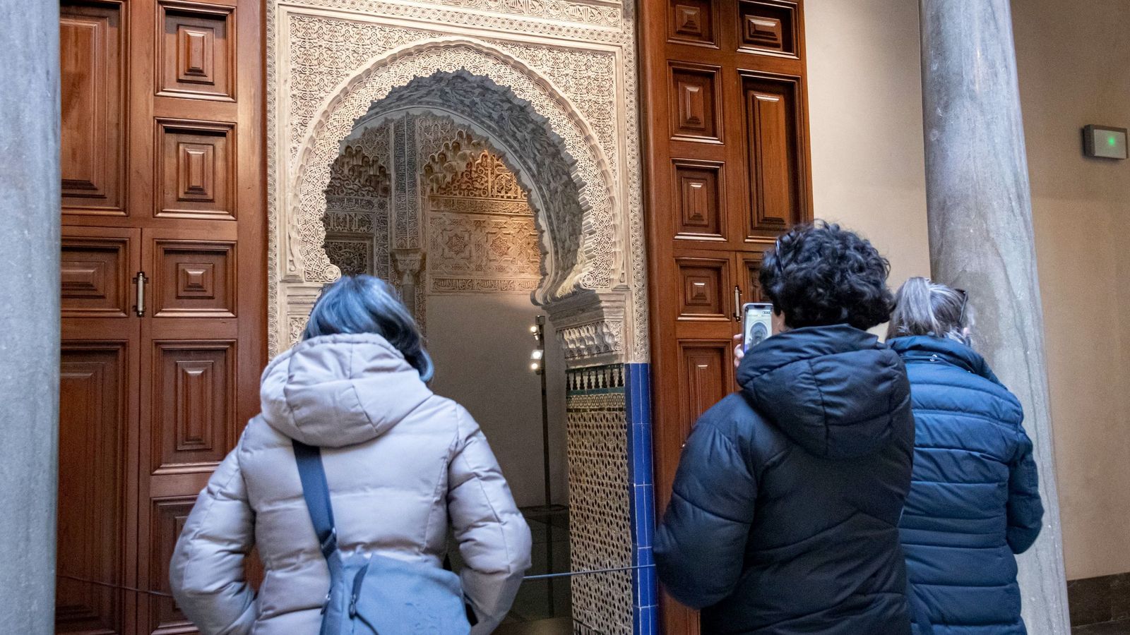 Varias personas se paran a observar el interior del Palacio de la Madraza.