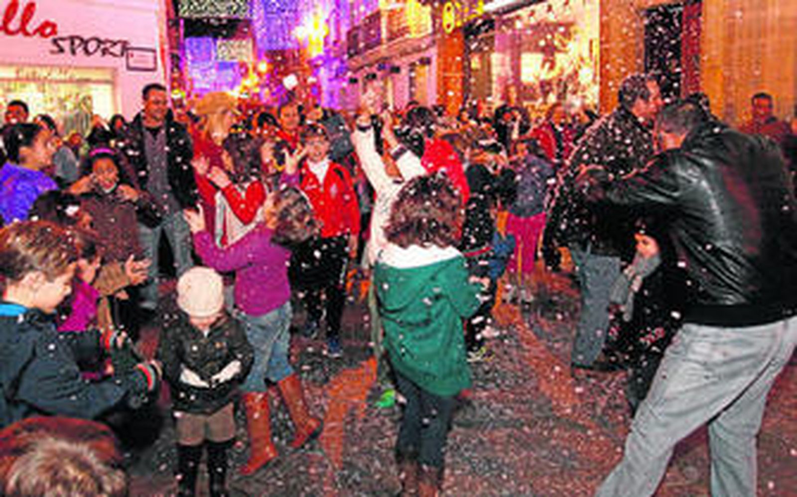 Niños y adultos, anoche durante la 'nevada' en la confluencia de las calles La Vega y La Fuente.