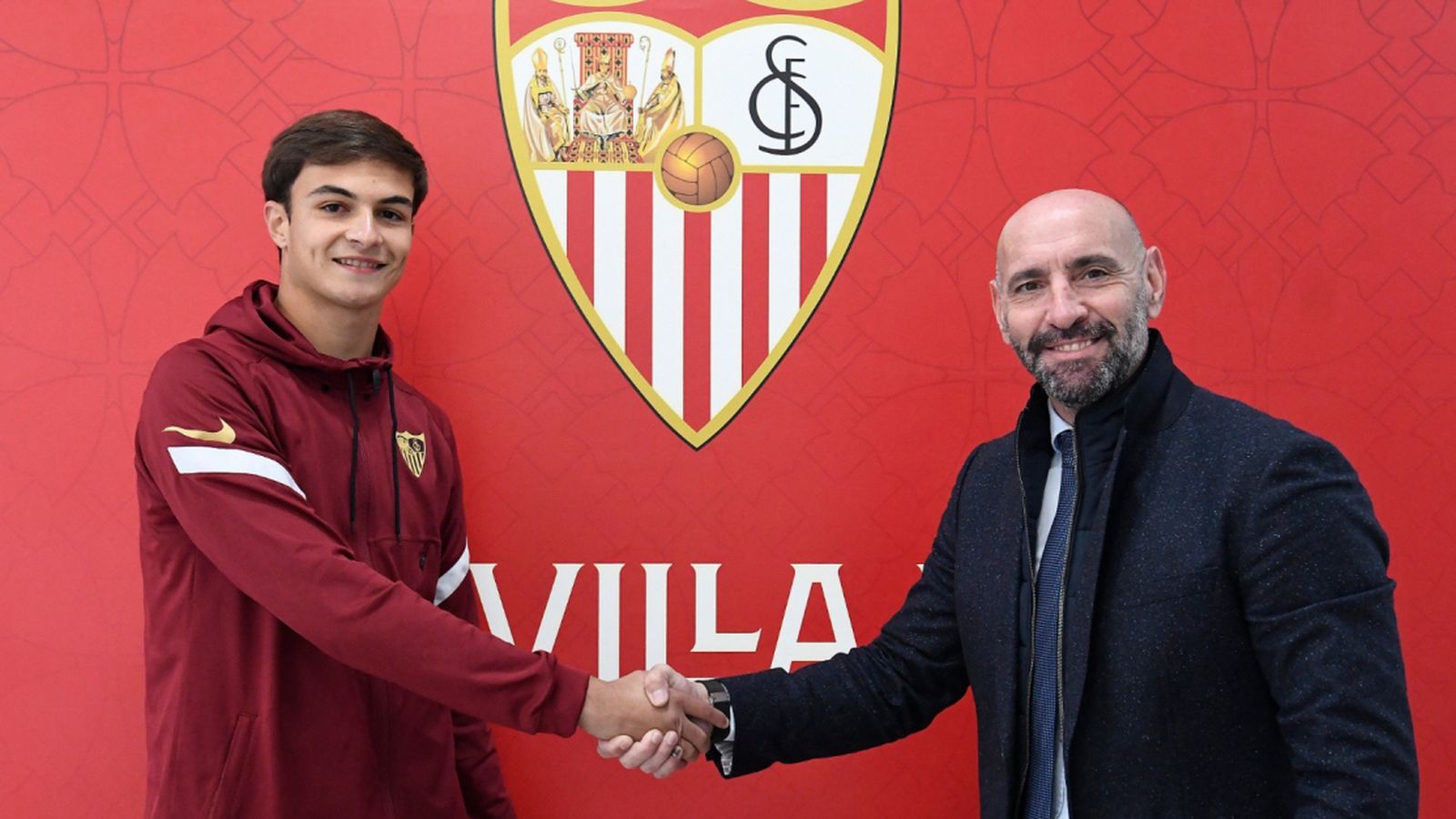 Lulo da Silva estrecha la mano de Monchi tras renovar hasta 2025 con el Sevilla.