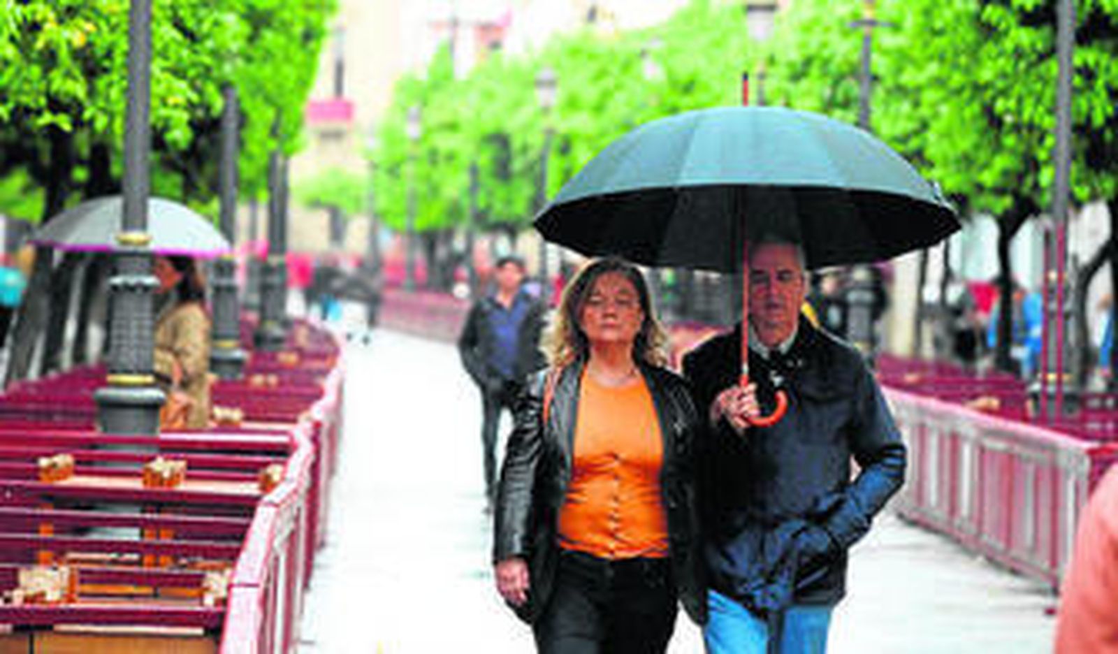 La calle Larga, ayer por la mañana, en plena lluvia con paraguas abiertos.