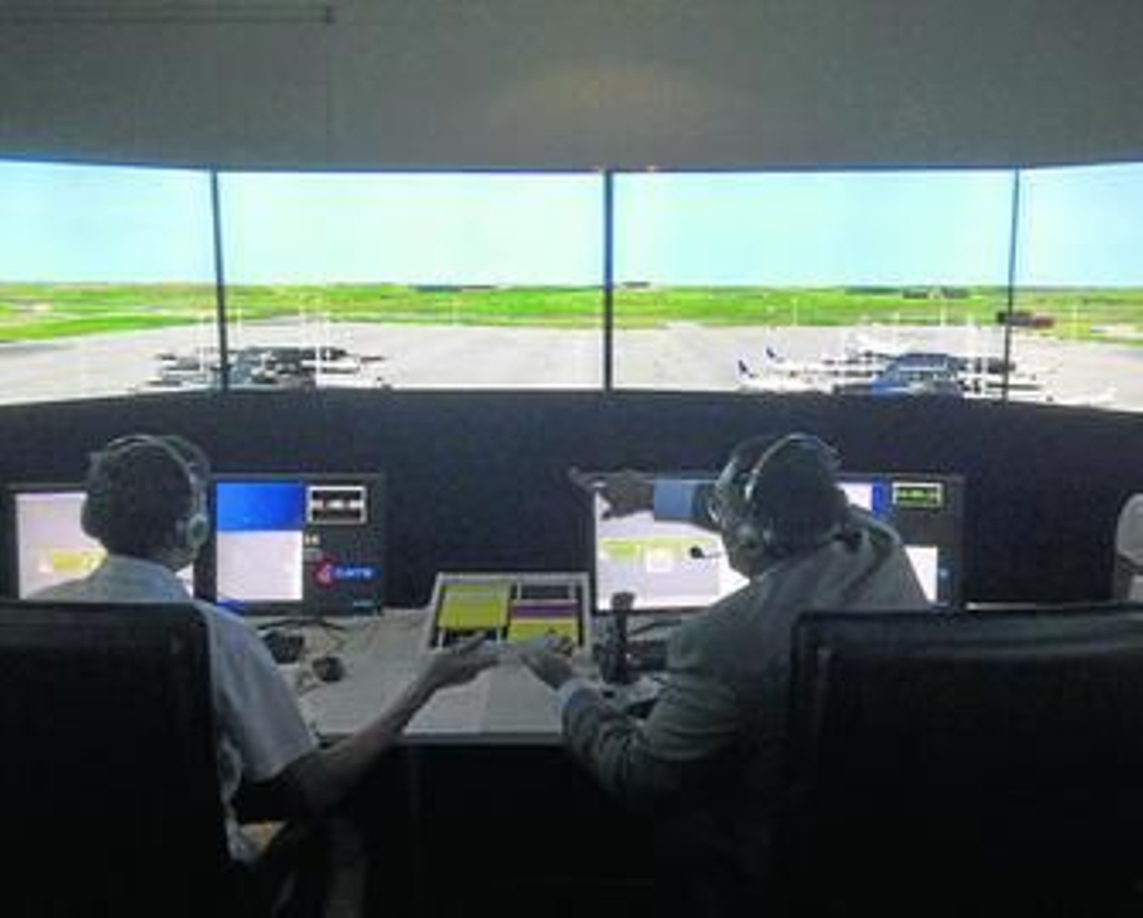 Un profesor de la Escuela de Pilotos de FTE da instrucciones a un alumno sobre el control aéreo en una pista virtual repleta de aviones.
