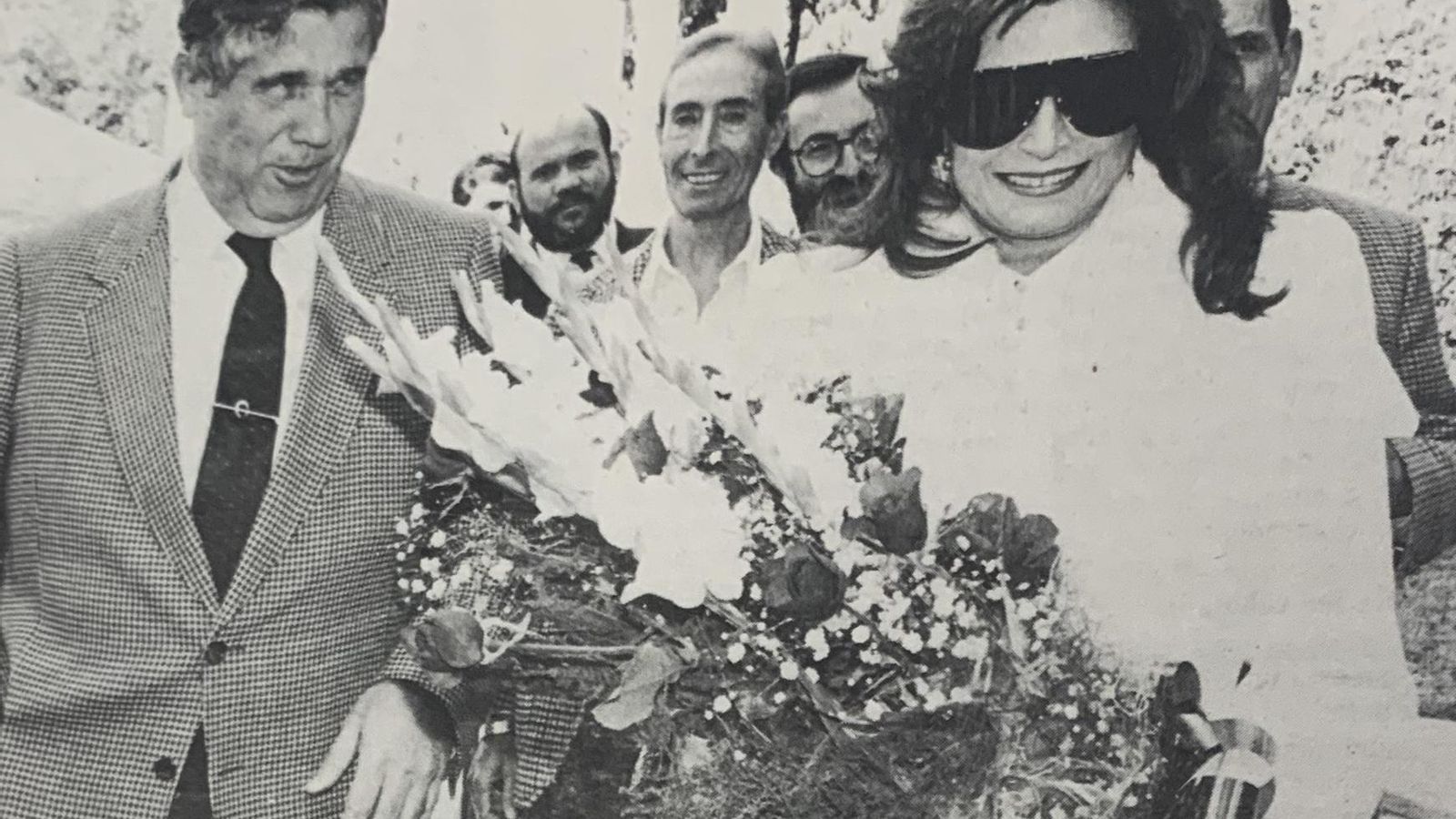 Rocío Jurado con un ramos de flores, junto al director general de la Caja y otros ejecutivos de la entidad.