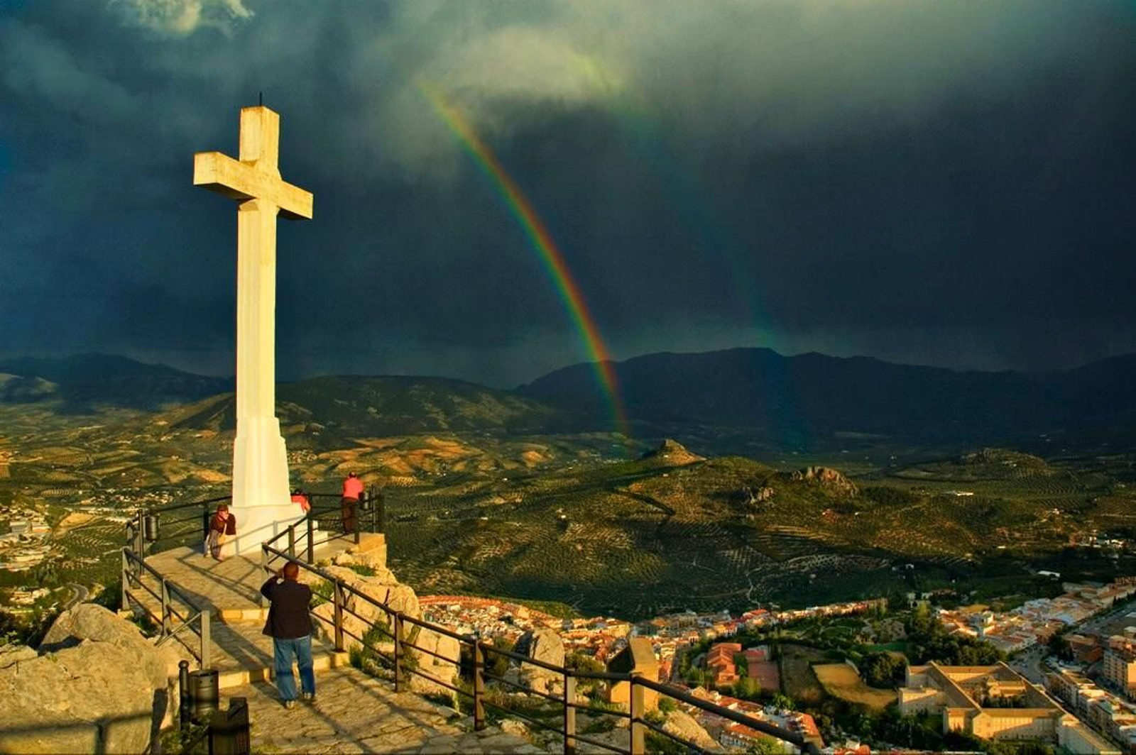 Un arcoiris se cuela en la estampa celestial desde la cruz del Castillo de Santa Catalina, en la capital.