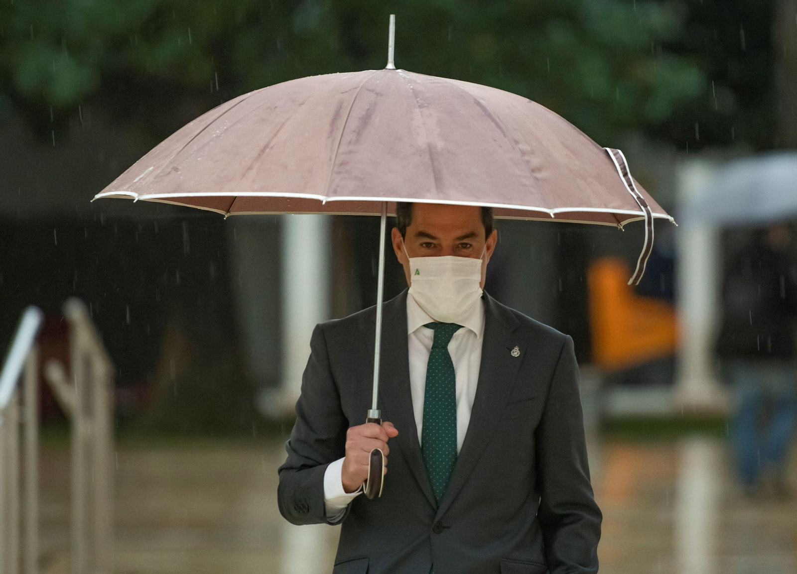 Juanma Moreno, bajo una intensa lluvia.