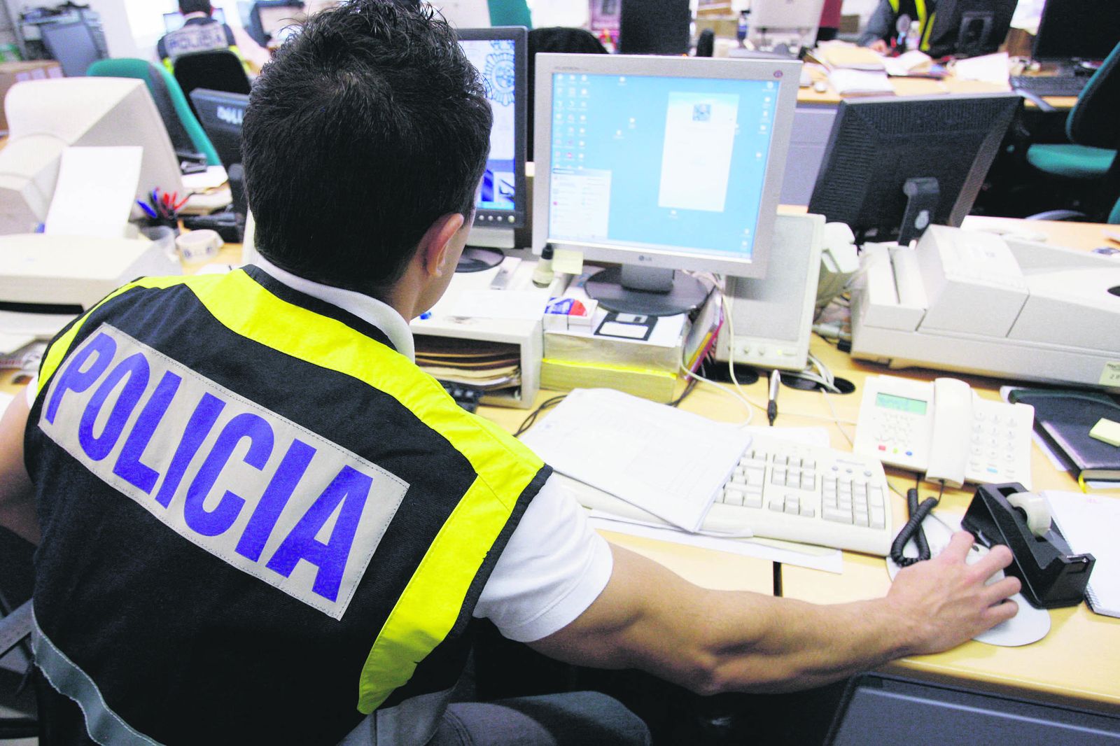 Un agente de la Policía Nacional trabajando con un equipo informático.