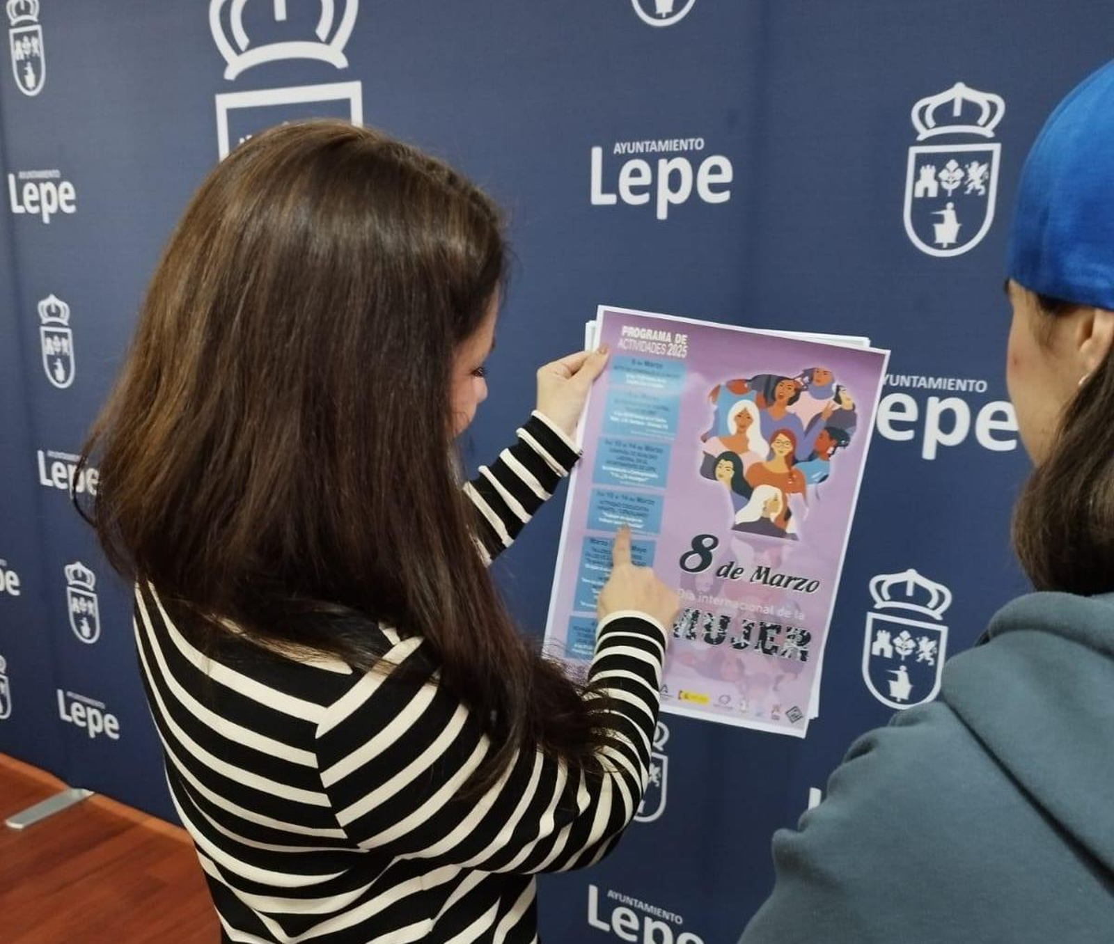 Carolina Reyes sosteniendo el cartel con la progamación del 8M en Lepe.