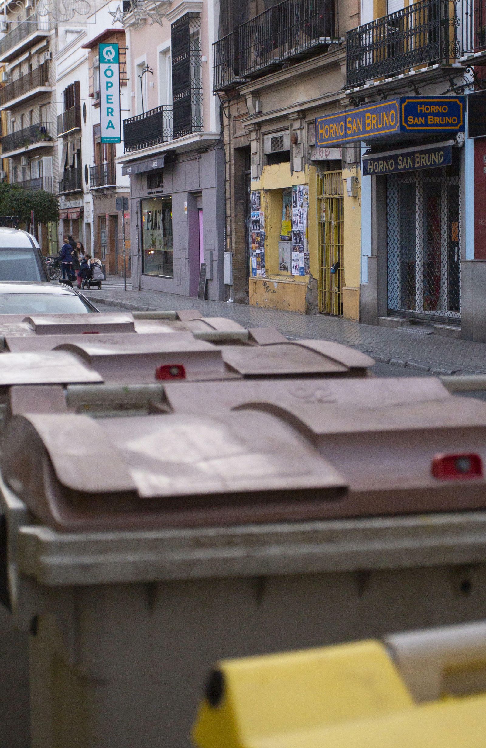 Un cubo de basura junto a varias viviendas de la calle Feria.