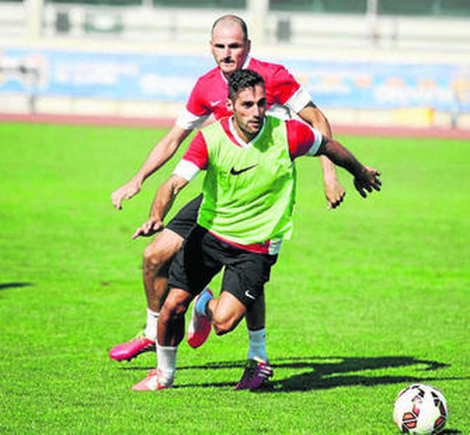 Trujillo se dirige a por un balón en un entrenamiento, con la mirada de Fernando Soriano por detrás.