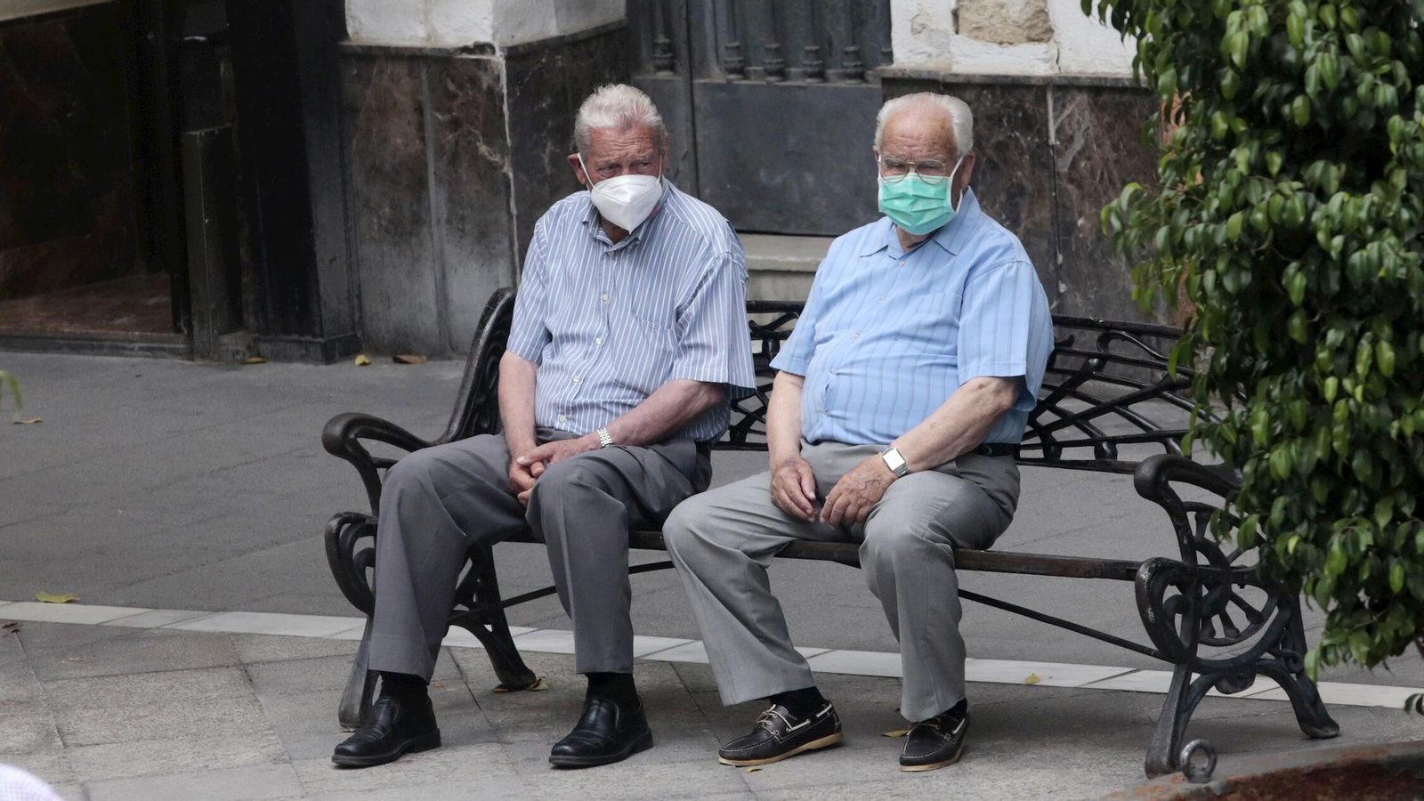 Ciudadanos con la mascarilla, que a partir de este sábado deja de ser obligatoria, sentados en un banco del centro.
