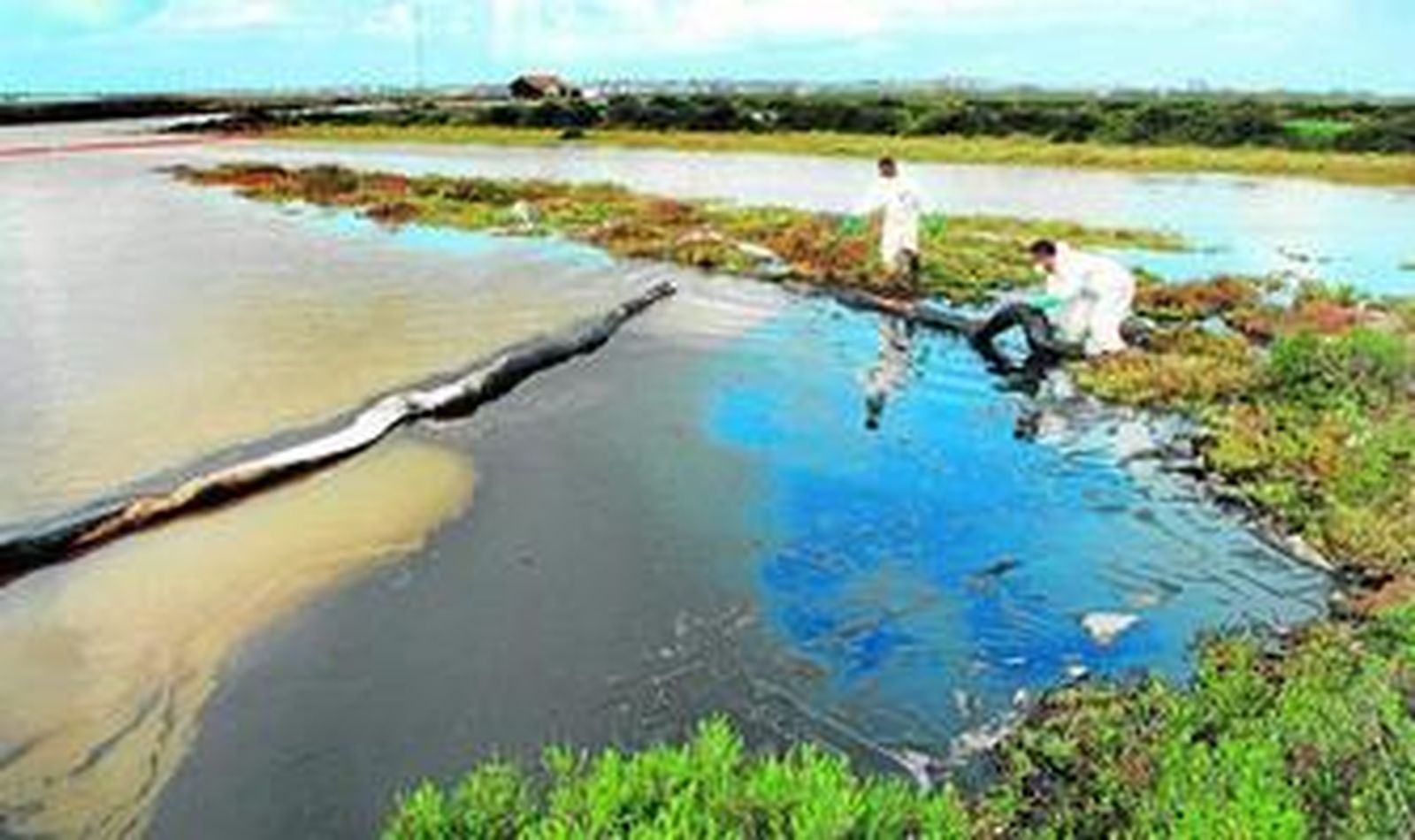 Dos operarios de la Consejería de Medio Ambiente, ayer frente a una gran mancha de una mezcla de gasoil, aceite y detergente.