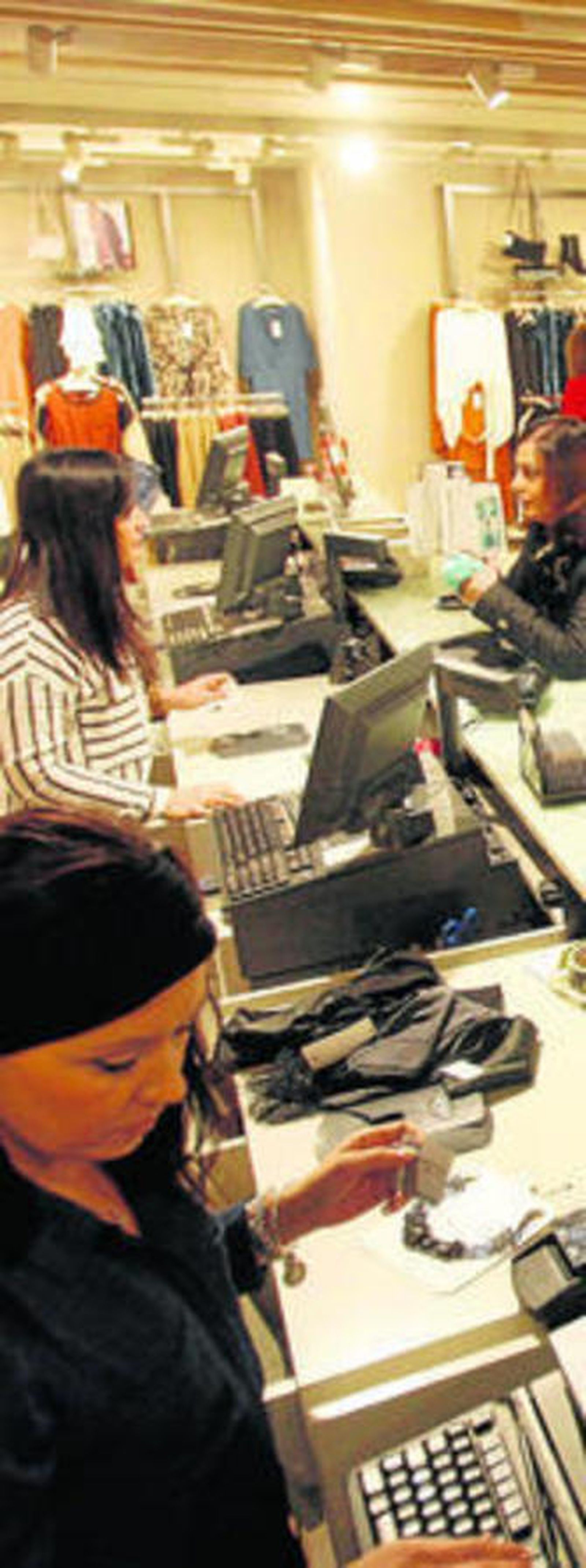 Dos mujeres atienden a varios clientes en una tienda de ropa.