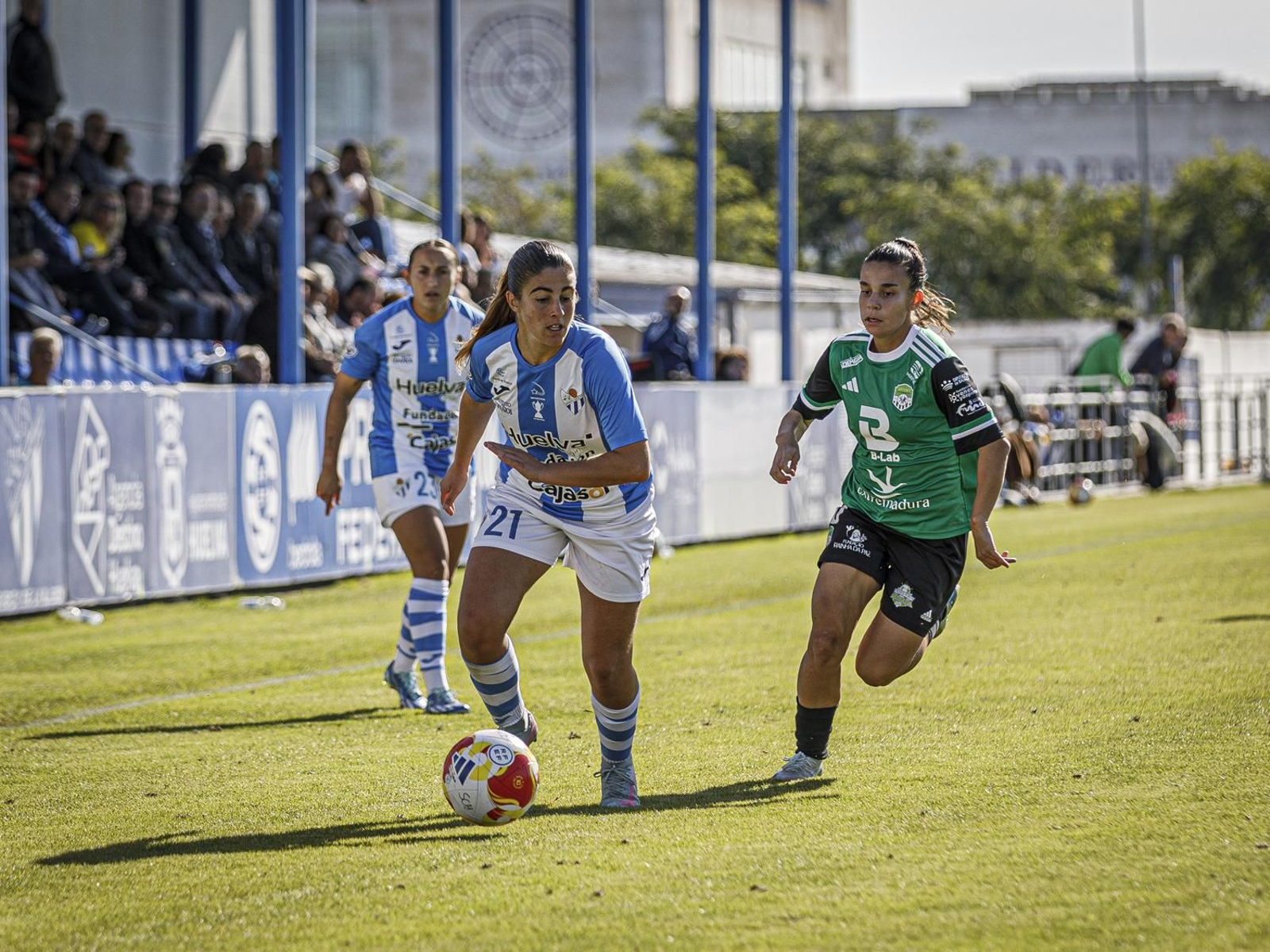 África conduce la pelota perseguida por un rival.