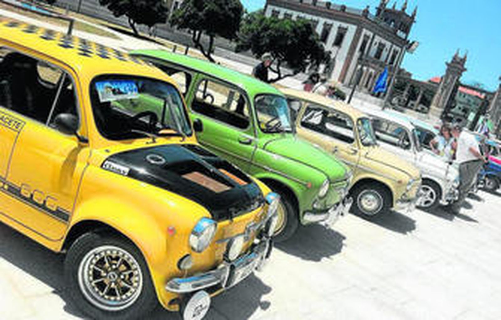 Varias personas observan la concentración de coches antiguos.