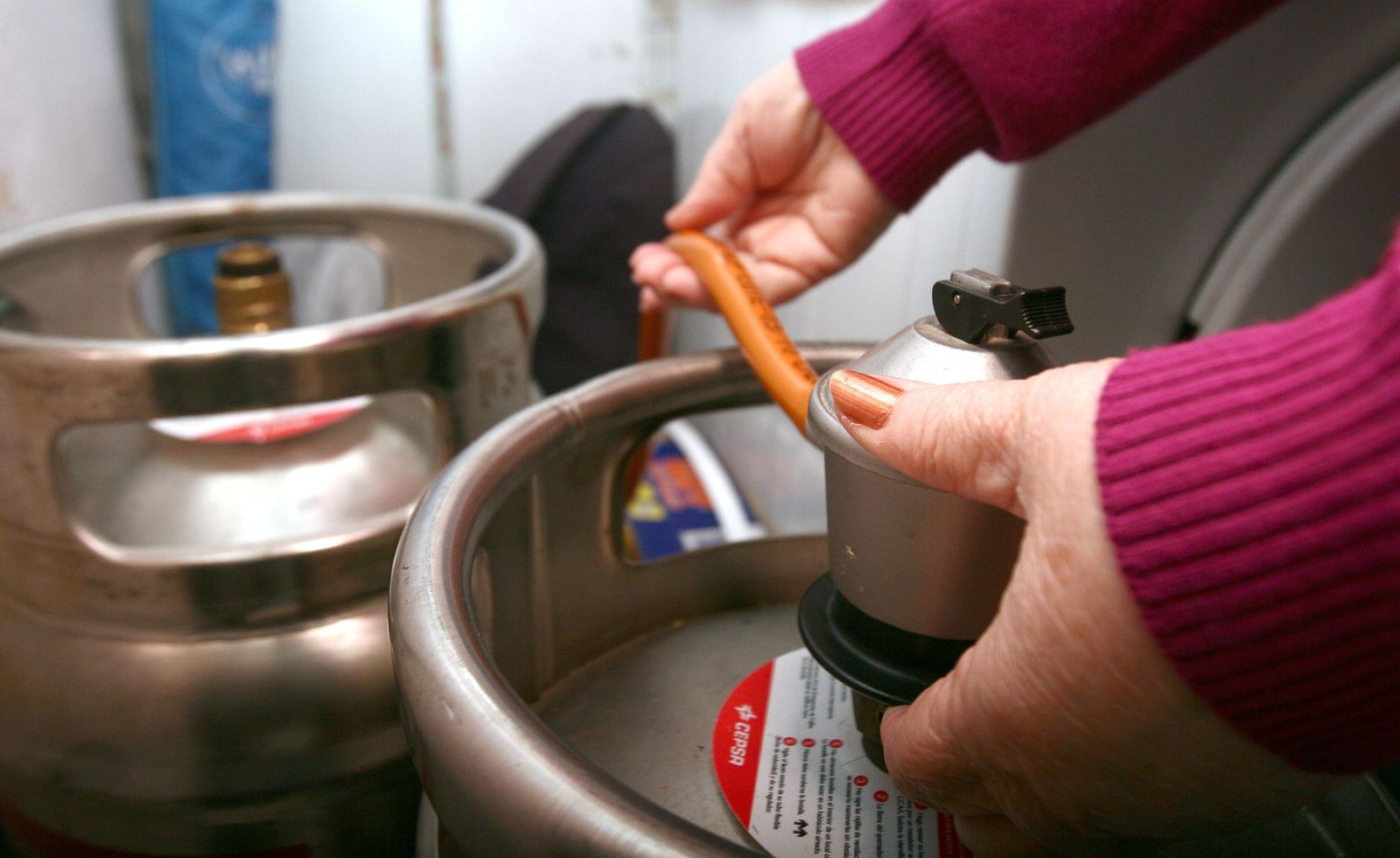 Una mujer manipula una bombona de butano en su domicilio.
