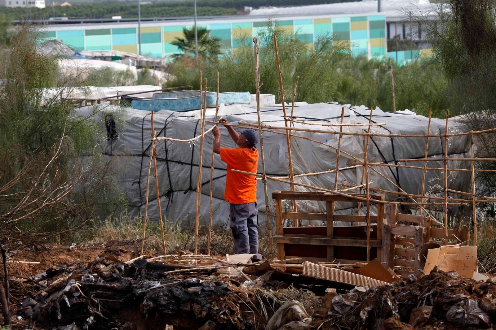 Un hombre reconstruye una chabola en un asentamiento onubense.