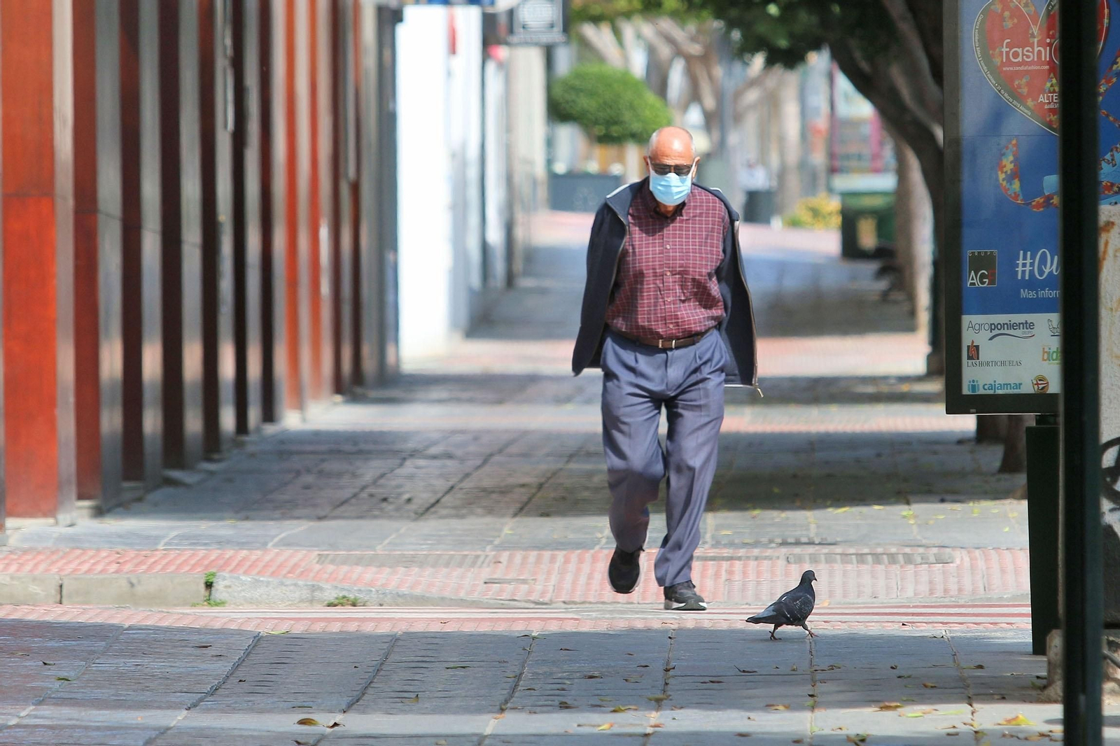 Un hombre camina por una calle vacía con una mascarilla.