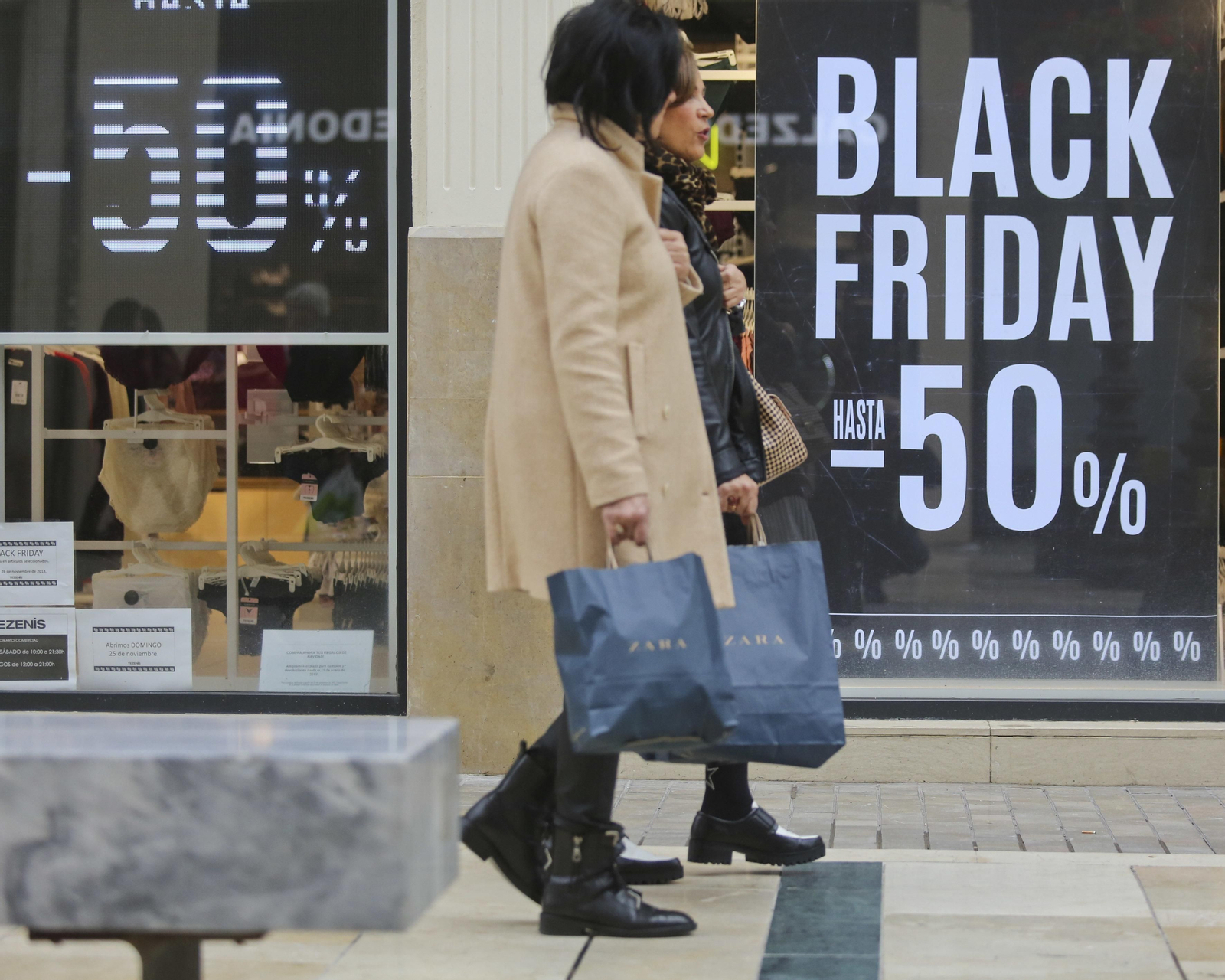 Dos mujeres pasean frente a una tienda de Larios.