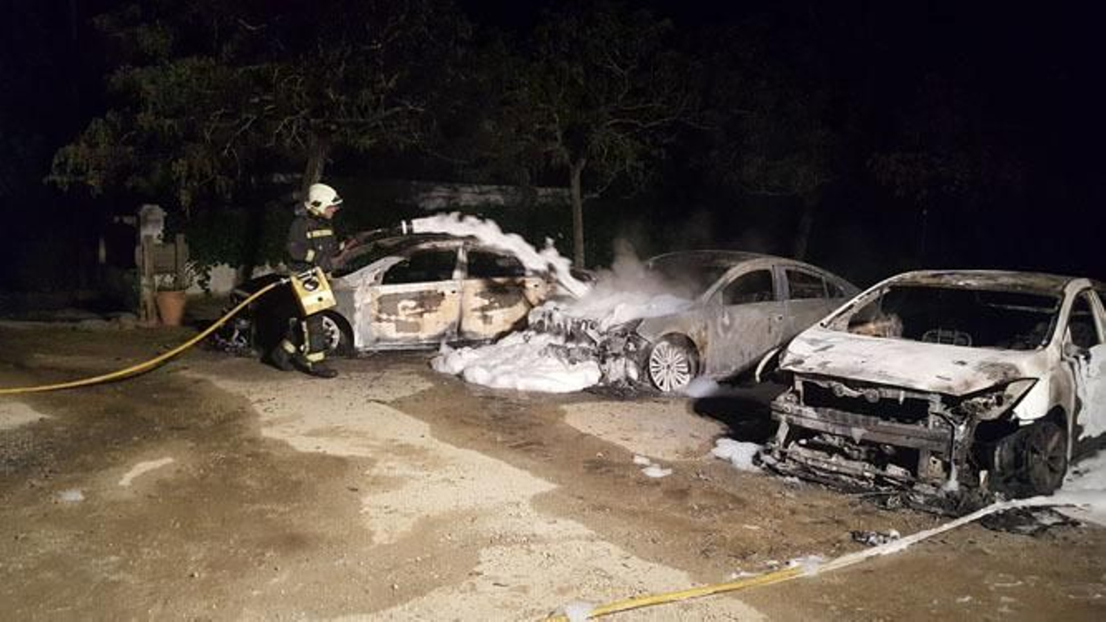 Los bomberos actúan sobre los coches para apagar el fuego.