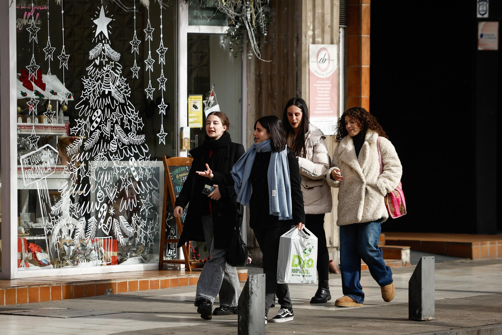 Varias amigas pasean abrigadas por el centro de Granada.