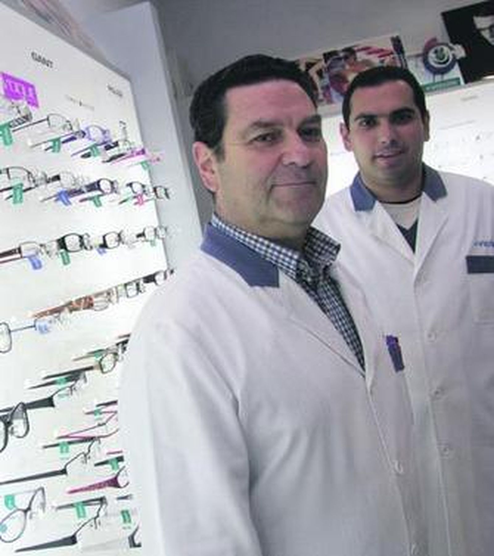 Manuel Romero posa con su hijo Javier en su óptica.