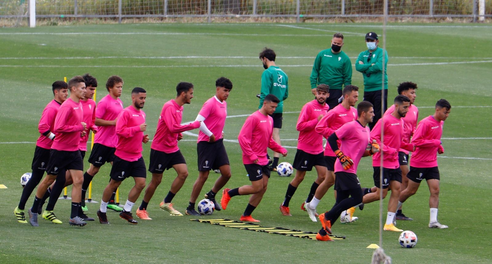 Los jugadores del Córdoba B calientan bajo la atenta mirada de su técnico, David Ortega.