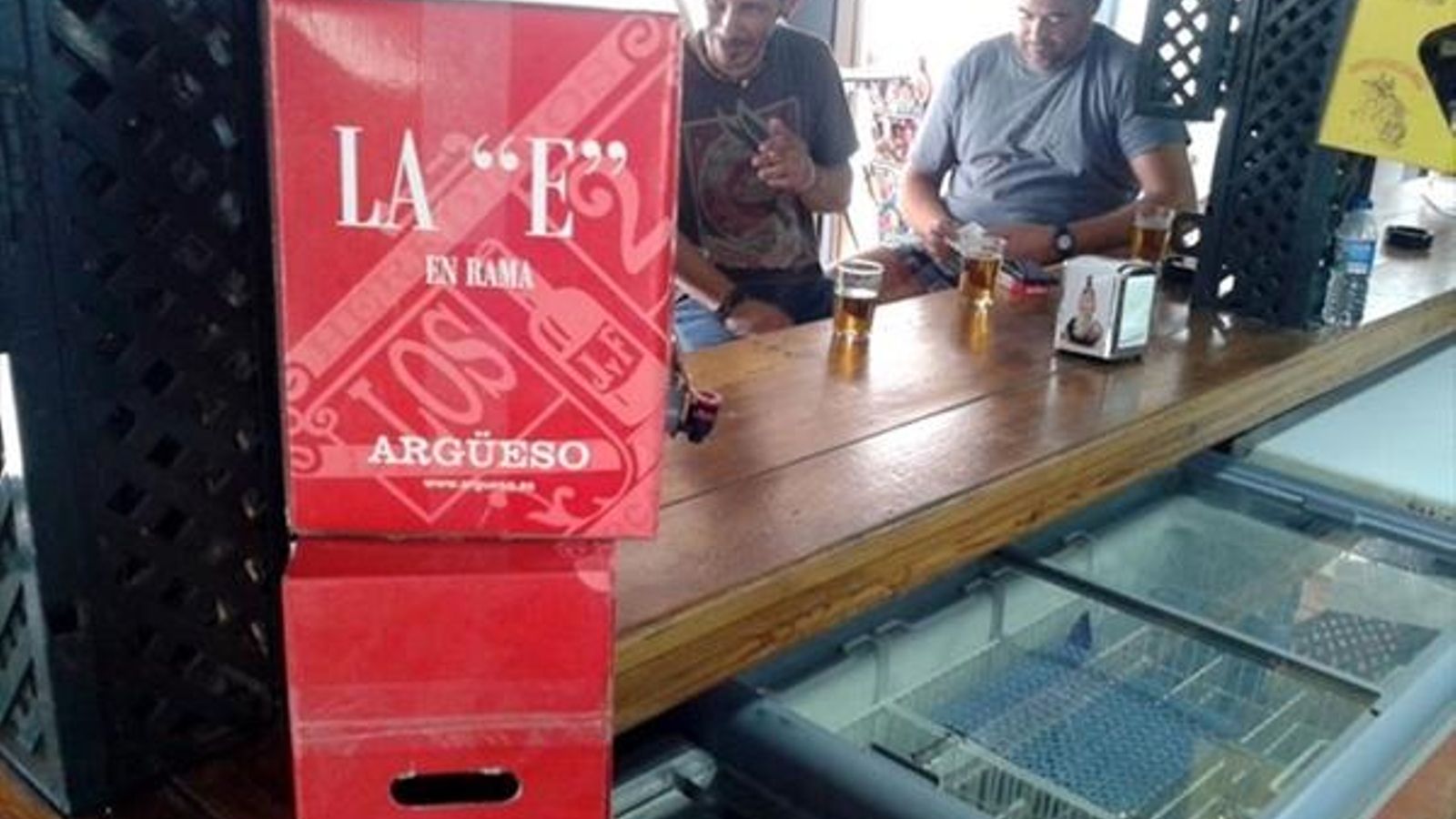 Clientes de un bar de Sanlúcar, conversan en la barra sobre la que descansa un 'Bag in Box' de una bodega sanluqueña. Clientes de un bar de Sanlúcar, conversan en la barra sobre la que descansa un 'Bag in Box' de una bodega sanluqueña.
