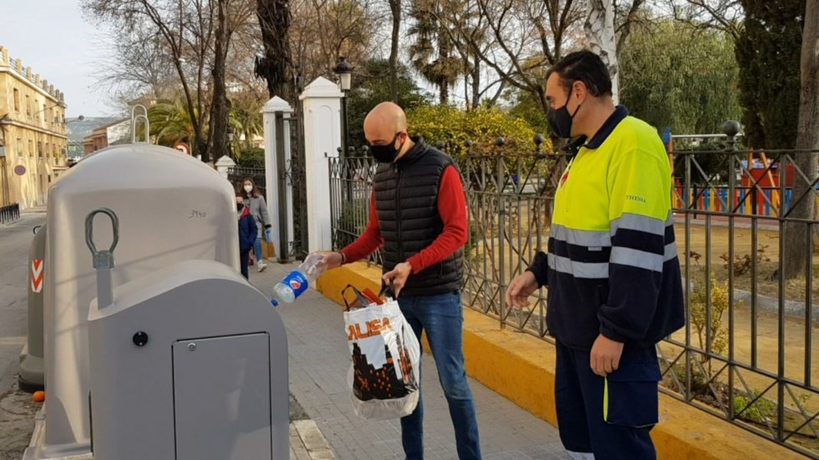 Una persona deposita basura en un contenedor en Lucena.
