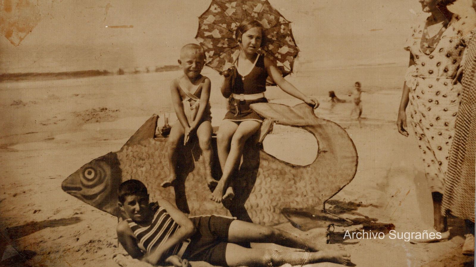 Los niños sobre un gran pez en la playa.