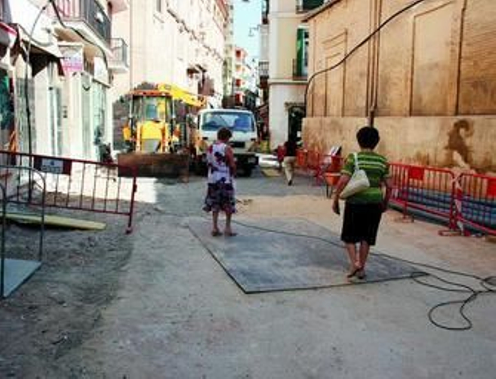 Dos mujeres atraviesan la calle Lucena en obras.