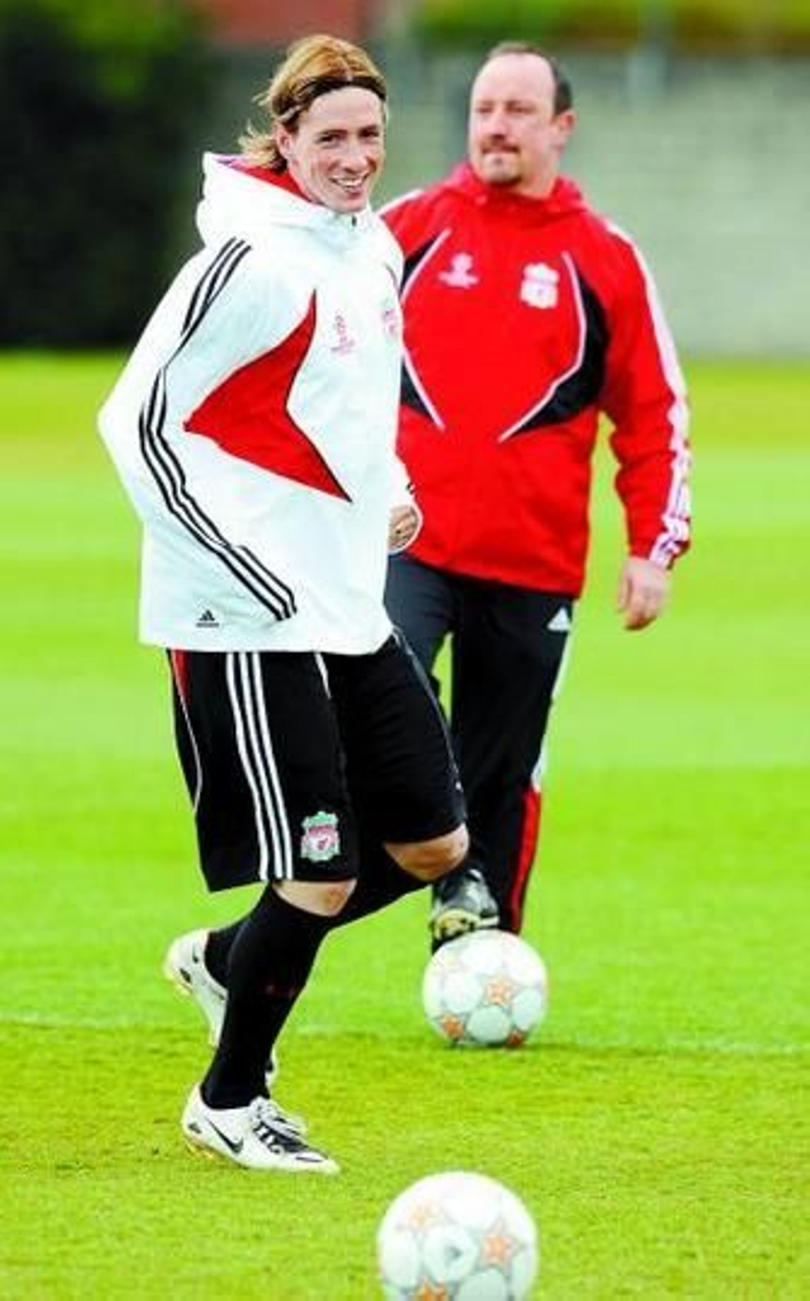 Fernando Torres sonríe mientras entrena delante de Benítez.